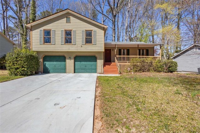 tri-level home featuring covered porch, an attached garage, concrete driveway, and a front yard