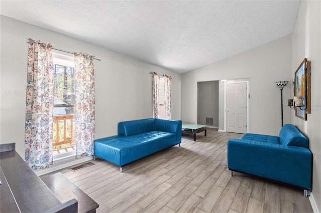 living room featuring a textured ceiling, wood finished floors, vaulted ceiling, and baseboards