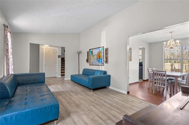 living area featuring a chandelier, wood finished floors, baseboards, lofted ceiling, and a textured ceiling
