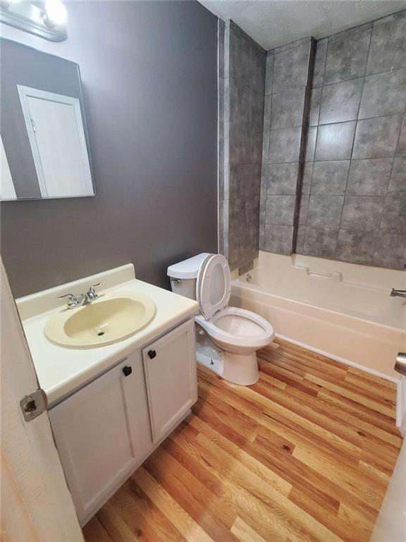 full bathroom featuring wood-type flooring, vanity, toilet, and tiled shower / bath