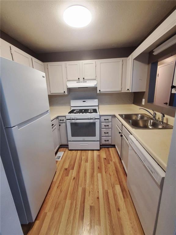 kitchen featuring white cabinetry, sink, white appliances, and light wood-type flooring