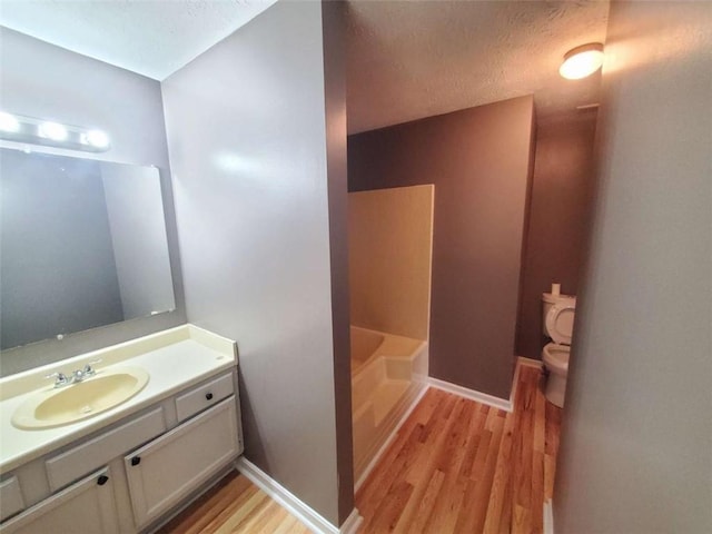 bathroom with hardwood / wood-style floors, vanity, a textured ceiling, and toilet