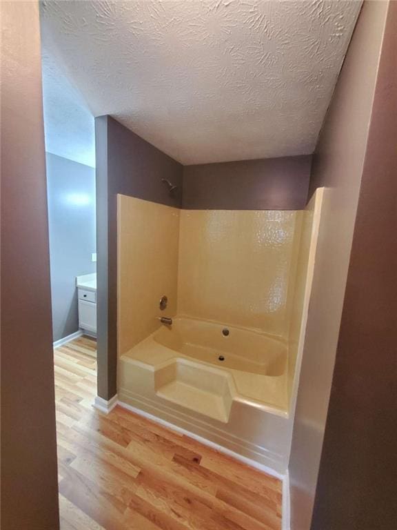 bathroom with washtub / shower combination, a textured ceiling, and hardwood / wood-style flooring