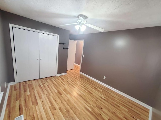 unfurnished bedroom with a textured ceiling, ceiling fan, light hardwood / wood-style flooring, and a closet