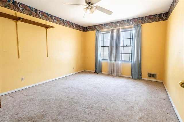 carpeted empty room with baseboards, a ceiling fan, and visible vents