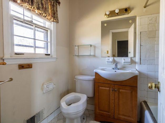 full bath featuring toilet, vanity, and visible vents