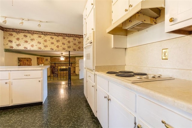 kitchen with white appliances, dark floors, white cabinets, light countertops, and wallpapered walls