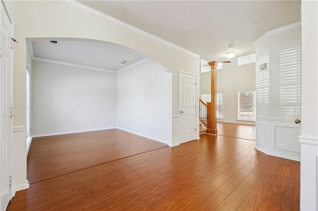 empty room with hardwood / wood-style floors, crown molding, and decorative columns