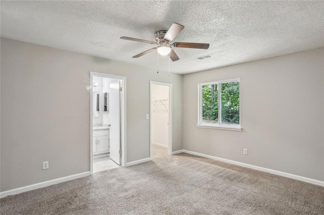 1050 Chapman Cir, Stone Mountain, GA 30088 - unfurnished bedroom featuring a spacious closet, light carpet, a closet, a textured ceiling, and ensuite bath