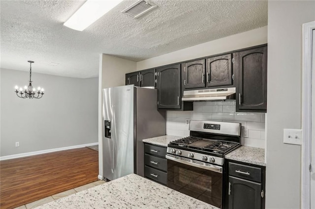 1050 Chapman Cir, Stone Mountain, GA 30088 - kitchen featuring stainless steel appliances, under cabinet range hood, backsplash, a textured ceiling, and a chandelier