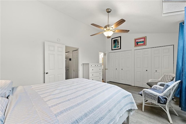 bedroom with ceiling fan, high vaulted ceiling, multiple closets, and light wood-type flooring