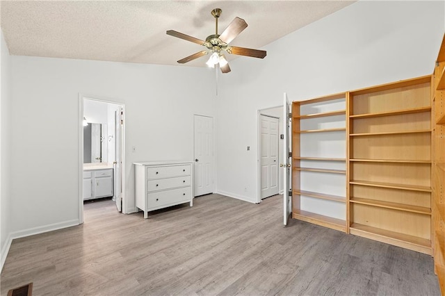 unfurnished bedroom with ensuite bath, ceiling fan, high vaulted ceiling, a textured ceiling, and light wood-type flooring