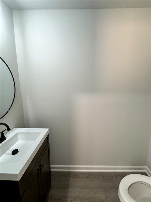 1341 E Atlanta Rd E, Stockbridge, GA 30281 - half bath with vanity, toilet, baseboards, and wood finished floors