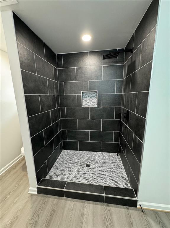 1341 E Atlanta Rd E, Stockbridge, GA 30281 - full bath with wood finished floors, a tile shower, baseboards, toilet, and recessed lighting