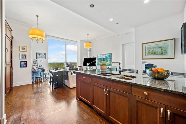 kitchen featuring pendant lighting, sink, dark stone counters, and dark hardwood / wood-style floors