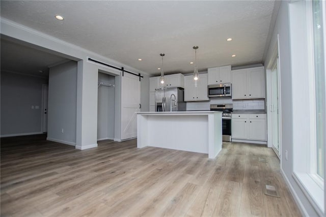 74 Preacher Smith Rd, Silver Creek, GA 30173 - kitchen with stainless steel appliances, a barn door, light wood-type flooring, white cabinets, and baseboards