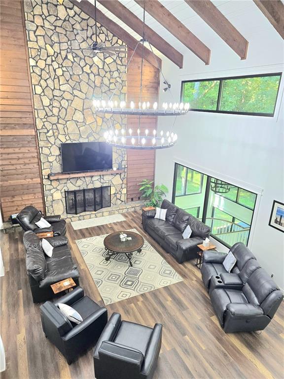 2900 Orchard Rd SW, Conyers, GA 30094 - living area with beam ceiling, wood finished floors, high vaulted ceiling, a stone fireplace, and a chandelier