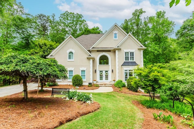 traditional home with stucco siding, french doors, and a front lawn