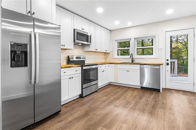 578 Cedar Ave, Atlanta, GA 30318 - kitchen featuring appliances with stainless steel finishes, dark wood-style floors, wooden counters, decorative backsplash, and a sink