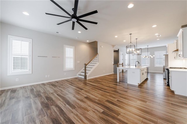 kitchen with an island with sink, pendant lighting, ceiling fan, and dark hardwood / wood-style flooring