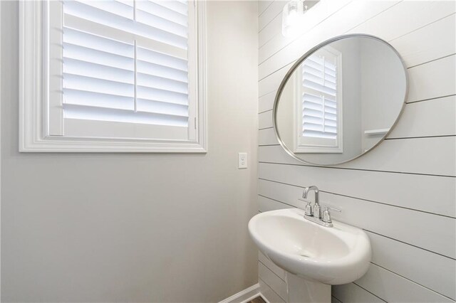 bathroom with plenty of natural light and wood walls