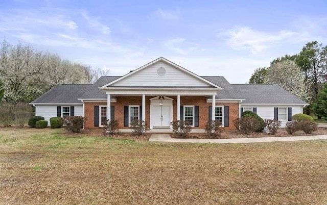 greek revival inspired property with a front lawn, a porch, and brick siding