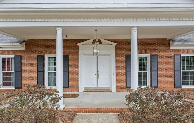 property entrance featuring covered porch and brick siding