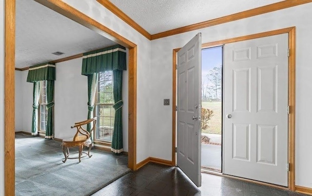 foyer featuring visible vents, crown molding, a textured ceiling, and baseboards