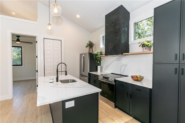 kitchen with a center island with sink, stainless steel appliances, light wood-type flooring, decorative backsplash, and sink