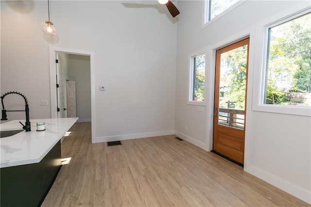 doorway to outside featuring sink, a high ceiling, ceiling fan, and light hardwood / wood-style floors