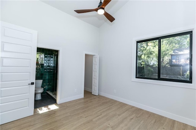 unfurnished bedroom with ensuite bathroom, high vaulted ceiling, ceiling fan, and light wood-type flooring