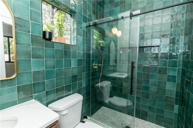 bathroom featuring toilet, a shower with shower door, tile walls, and vanity