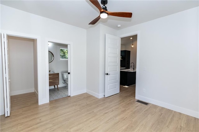 unfurnished bedroom featuring sink, ensuite bathroom, ceiling fan, and light hardwood / wood-style flooring