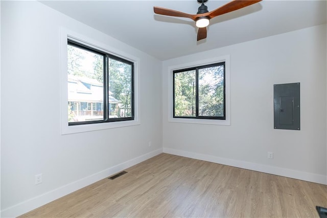 empty room featuring electric panel, light wood-type flooring, and ceiling fan