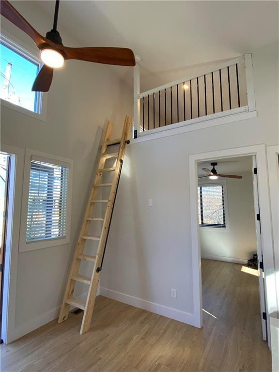 stairway with a high ceiling, wood-type flooring, and a healthy amount of sunlight