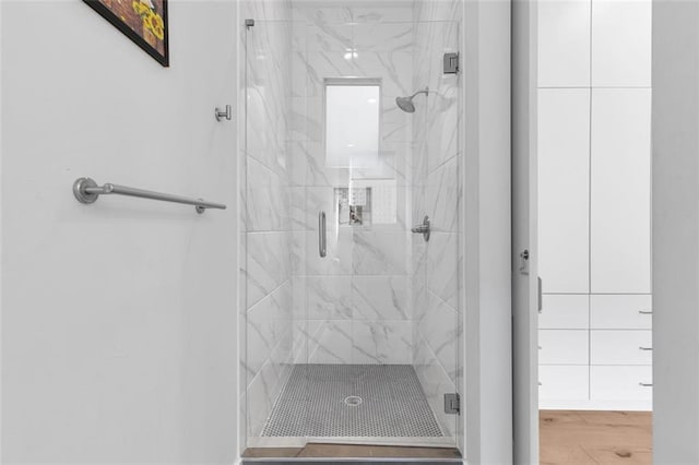 bathroom with a shower with shower door and wood-type flooring