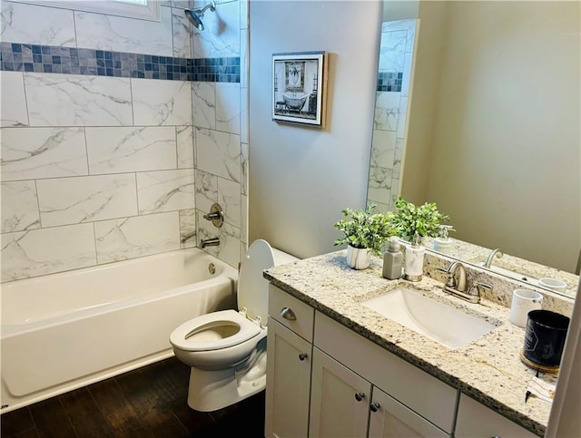 full bathroom with tiled shower / bath, vanity, toilet, and hardwood / wood-style floors