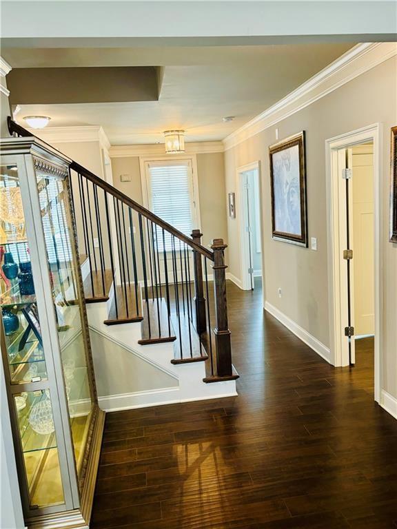 stairway with hardwood / wood-style floors and ornamental molding