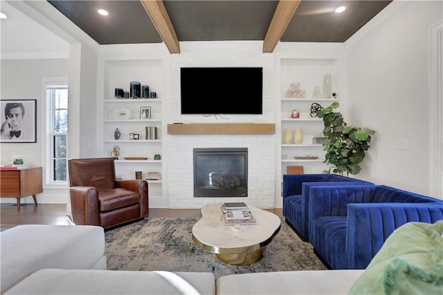 living room with a brick fireplace, built in shelves, and beamed ceiling