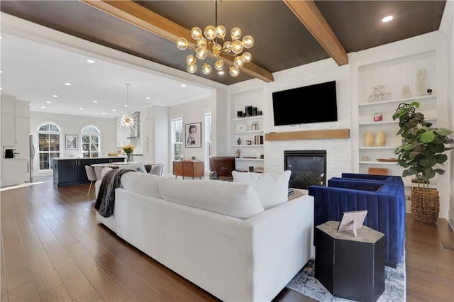 living room featuring a notable chandelier, dark hardwood / wood-style flooring, a fireplace, built in features, and beamed ceiling