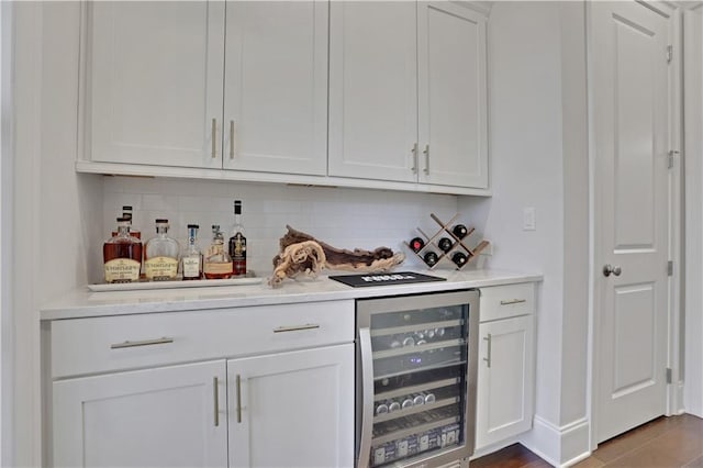 bar with wine cooler, white cabinets, and tasteful backsplash