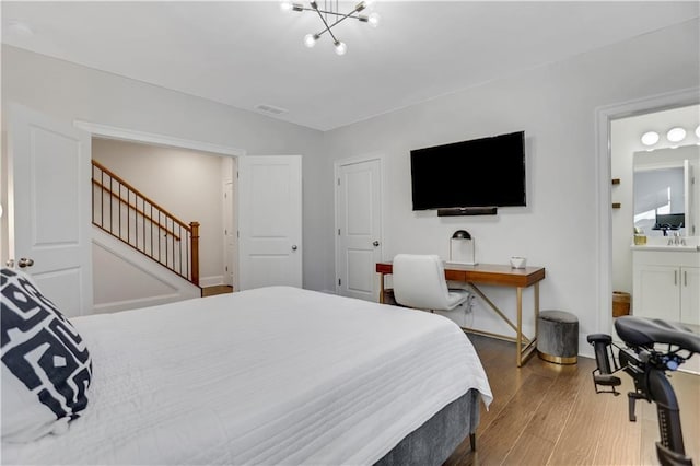 bedroom featuring a notable chandelier, hardwood / wood-style floors, and ensuite bath