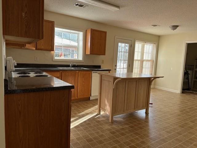 635 Beddick Ln, Atlanta, GA 30349 - kitchen featuring a textured ceiling, dishwasher, plenty of natural light, dark countertops, and a kitchen island