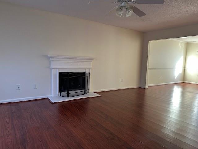 635 Beddick Ln, Atlanta, GA 30349 - unfurnished living room featuring a ceiling fan, wood finished floors, a fireplace with raised hearth, and baseboards