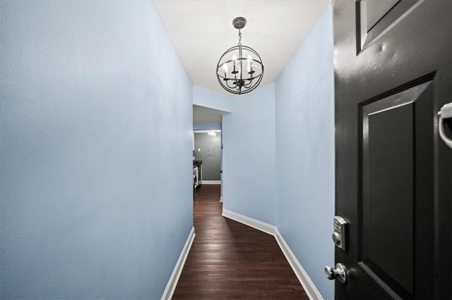 hallway with dark hardwood / wood-style flooring and a chandelier