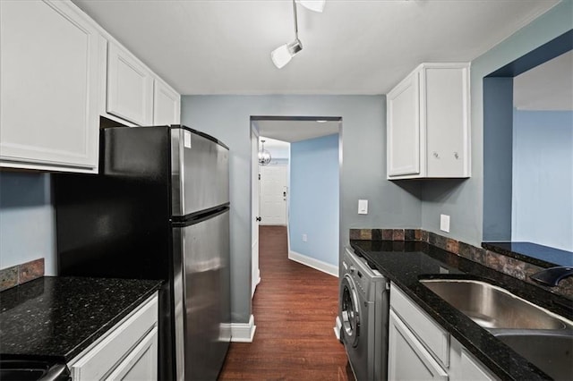 kitchen featuring sink, white cabinetry, dark stone countertops, dark hardwood / wood-style flooring, and washer / clothes dryer