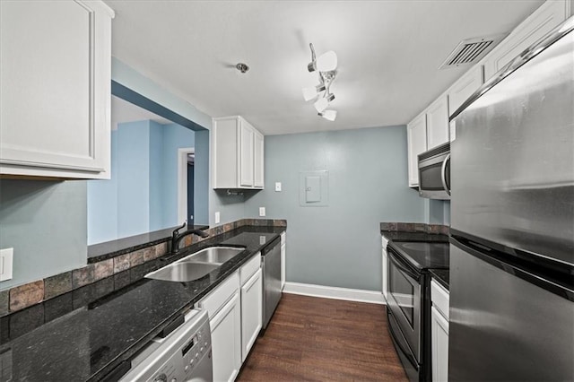 kitchen featuring appliances with stainless steel finishes, sink, dark stone countertops, white cabinets, and dark wood-type flooring