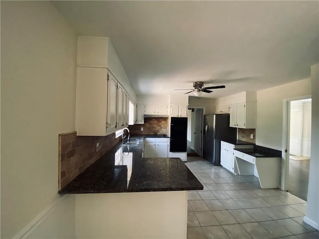 kitchen with a sink, tasteful backsplash, freestanding refrigerator, a peninsula, and white cabinets