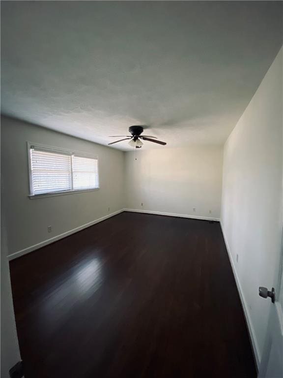 spare room featuring ceiling fan, baseboards, and dark wood-style flooring