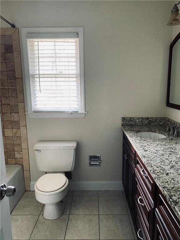 bathroom featuring baseboards, toilet, shower / bathing tub combination, tile patterned floors, and vanity